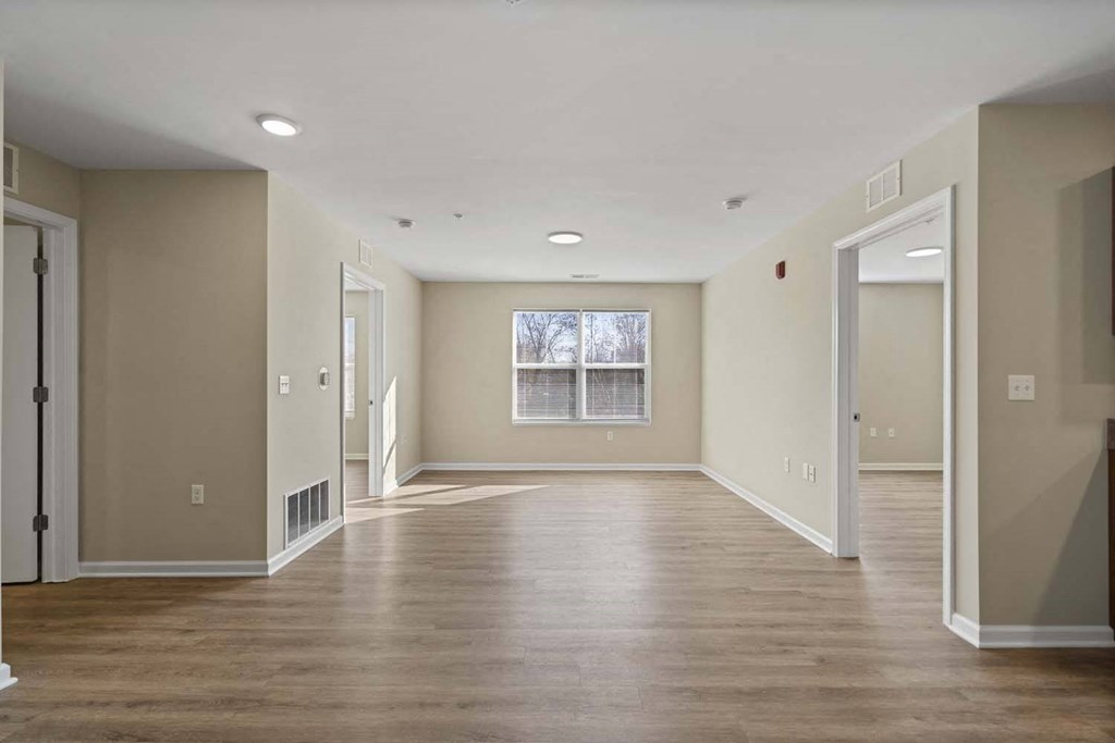 an empty living room with wood floors and a window