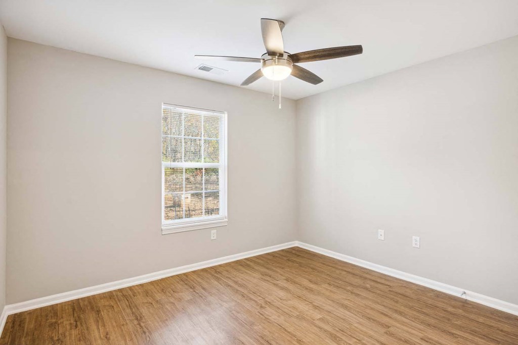 an empty living room with a ceiling fan and a window