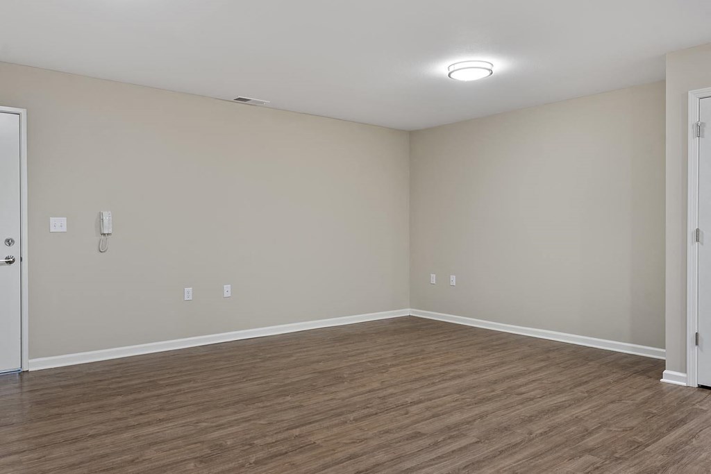 an empty living room with wood flooring and white walls