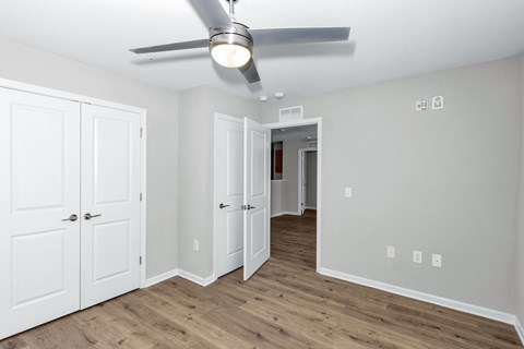 A room with a ceiling fan and white doors.