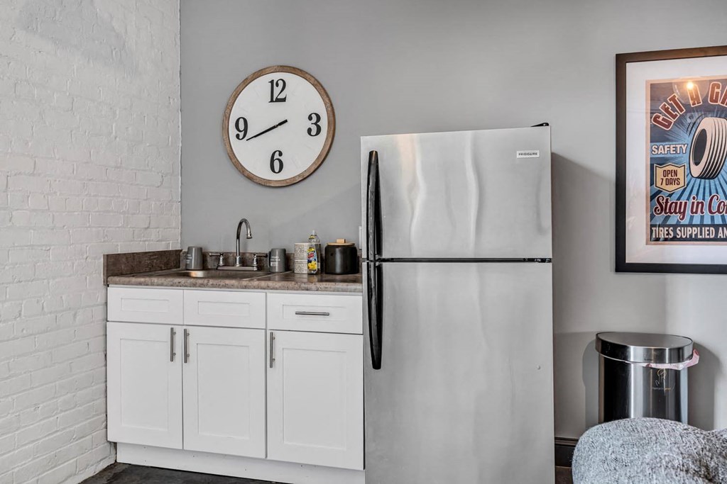 a kitchen with a sink refrigerator and a clock on the wall