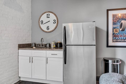 a kitchen with a refrigerator and a clock on the wall