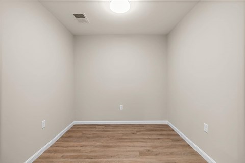 A room with wooden flooring and white walls.