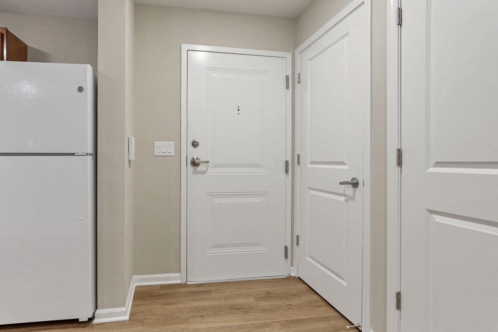 a hallway with white doors and a refrigerator