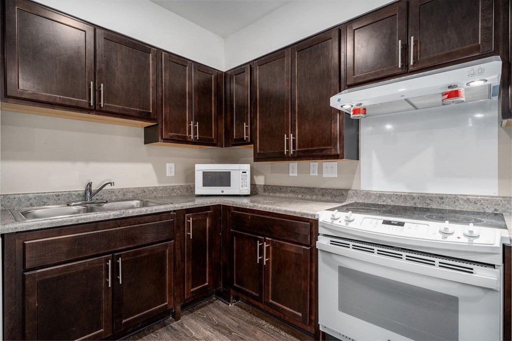 a kitchen with dark wood cabinets and white appliances