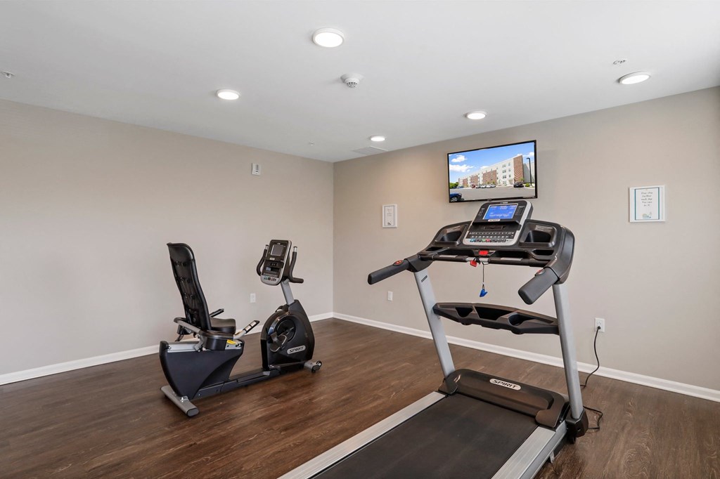 a home gym with two treadmills and a flat screen tv