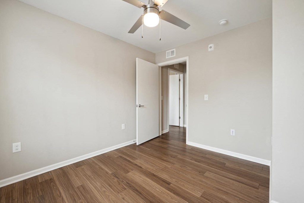 a bedroom with hardwood floors and a ceiling fan