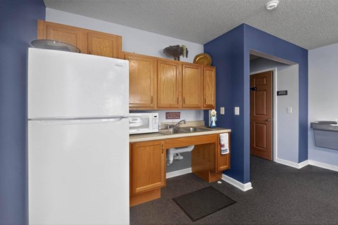 A kitchen with a white refrigerator and wooden cabinets.
