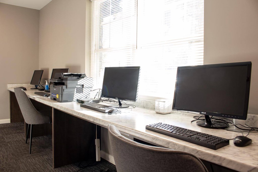 A white desk with two monitors and a keyboard.