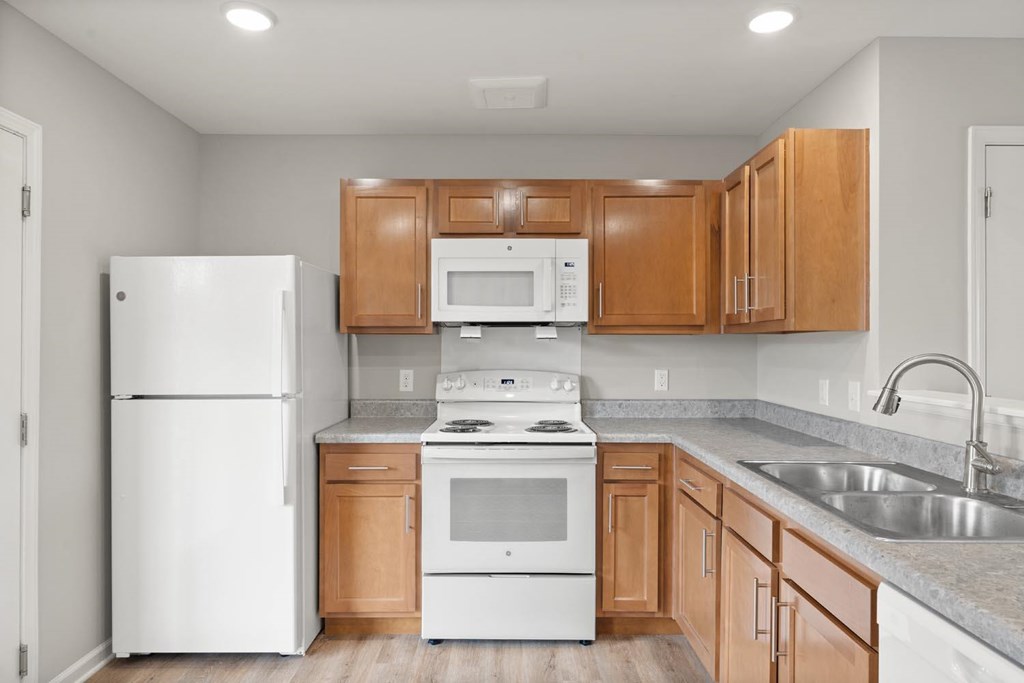 A kitchen with white appliances and wooden cabinets.