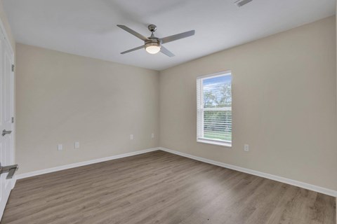 A room with a ceiling fan and a window with blinds.