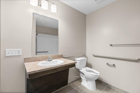 A bathroom with a toilet, sink, and mirror.