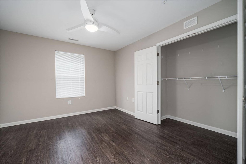 an empty bedroom with a closet and a ceiling fan