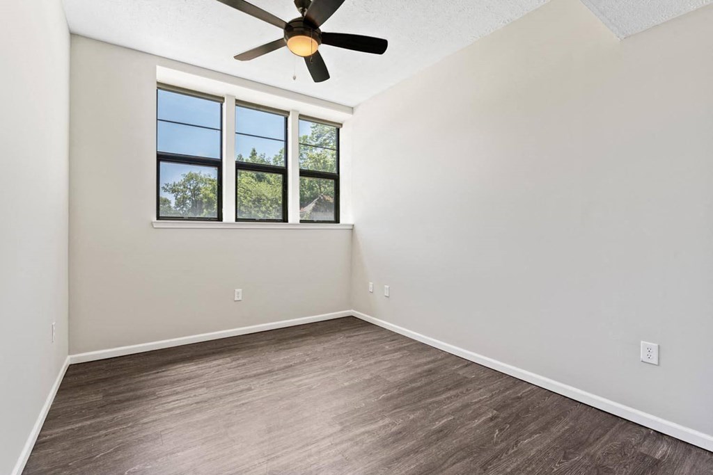 an empty living room with a ceiling fan and a window