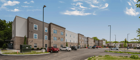 A street view of a residential area with apartment buildings and cars parked on the side of the road.