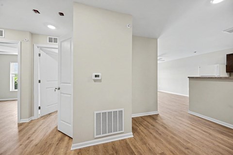A room with a white door and a white wall with a vent.