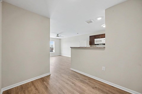 A spacious room with wooden floors and a countertop with a microwave.