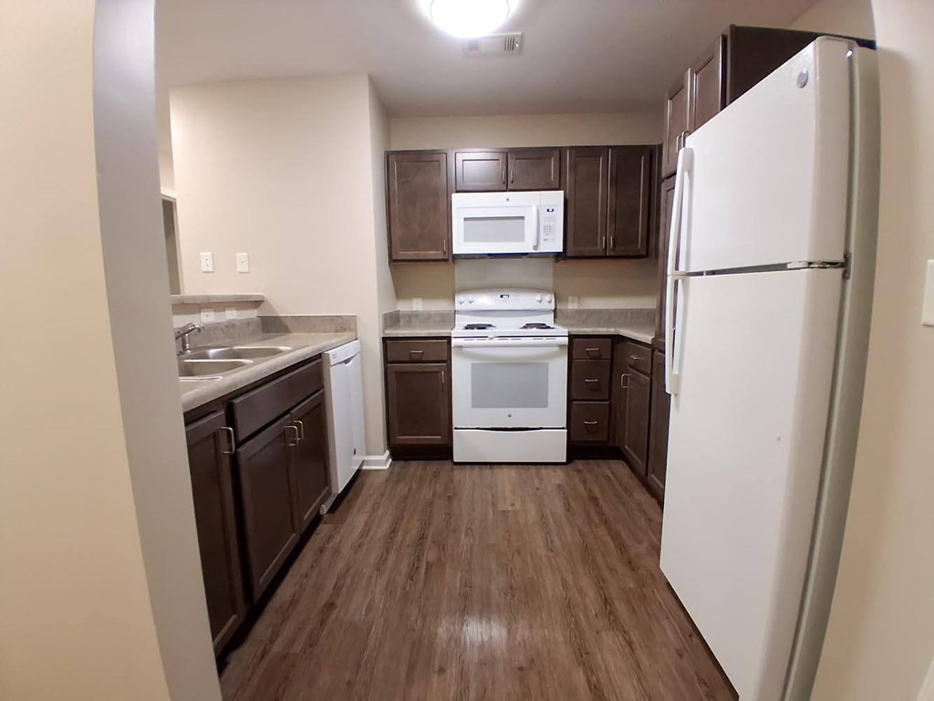A kitchen with a white refrigerator, white oven, and brown cabinets.