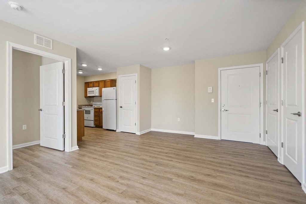 an empty living room and kitchen with white doors