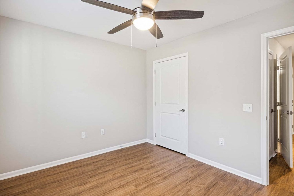 an empty living room with a ceiling fan and a door