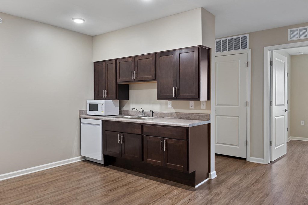 a kitchen with dark cabinets and a sink and a microwave