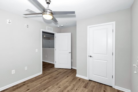 A room with a ceiling fan and two doors.