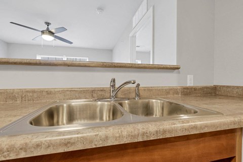 a kitchen with a sink and a ceiling fan