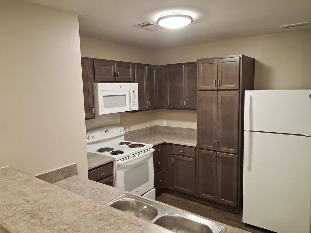 A kitchen with brown cabinets and a white fridge.