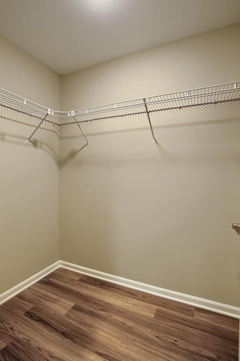 A walk-in closet with a wooden floor and metal racks.