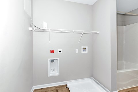 A white wall with a shelf and a white box with a red label on it.