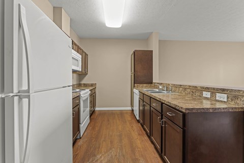 A kitchen with a white refrigerator and brown cabinets.