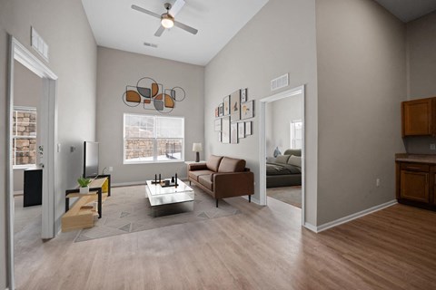 A living room with a brown couch, a coffee table, and a ceiling fan.