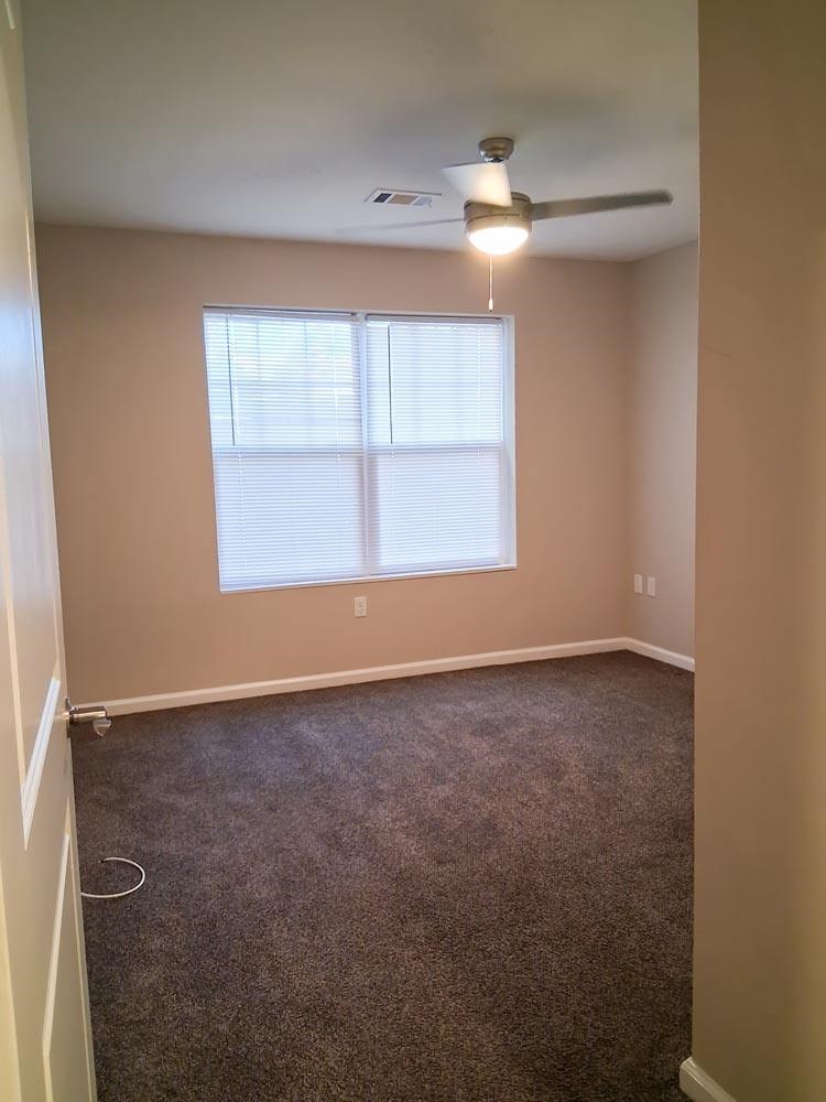 A room with a ceiling fan and a window with blinds.