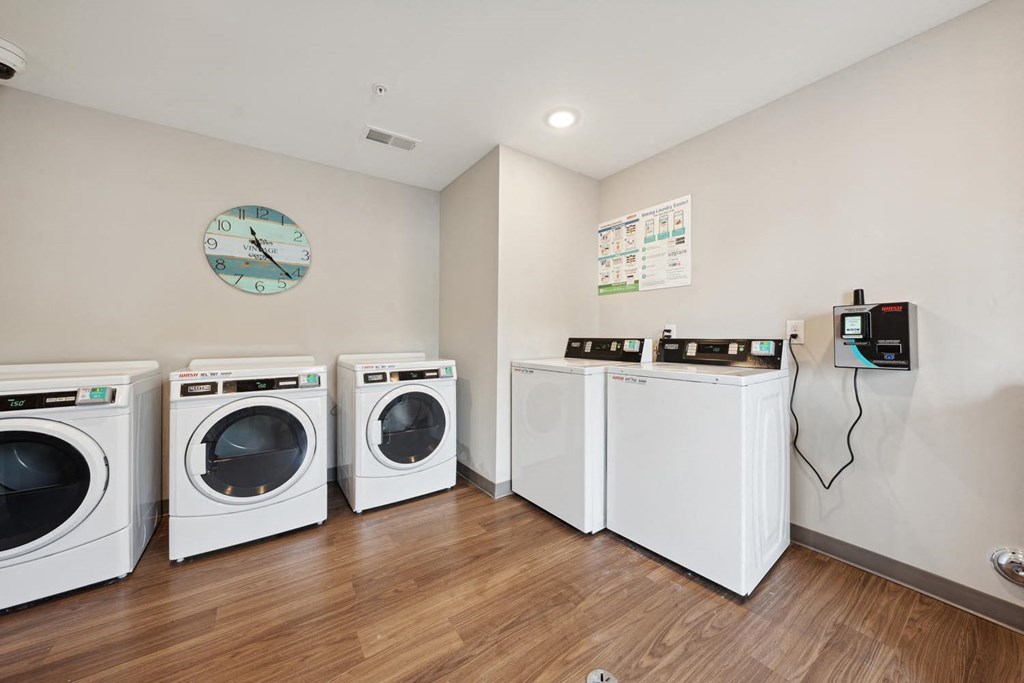 laundry room with four washing machines and a clock on the wall