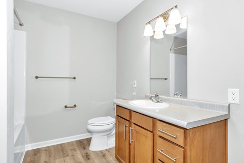 A white toilet sits under a mirror in a bathroom.