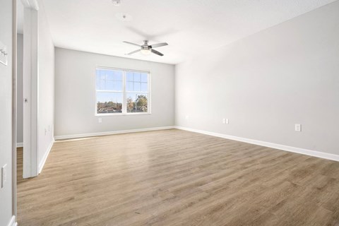 an empty living room with a ceiling fan and a window