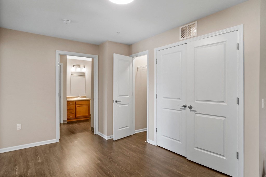 a bedroom with three doors and a bathroom in the background