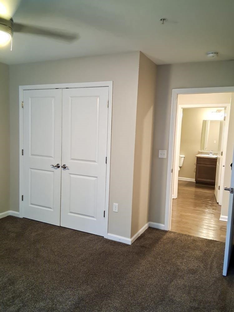 A room with a white door and a ceiling fan.