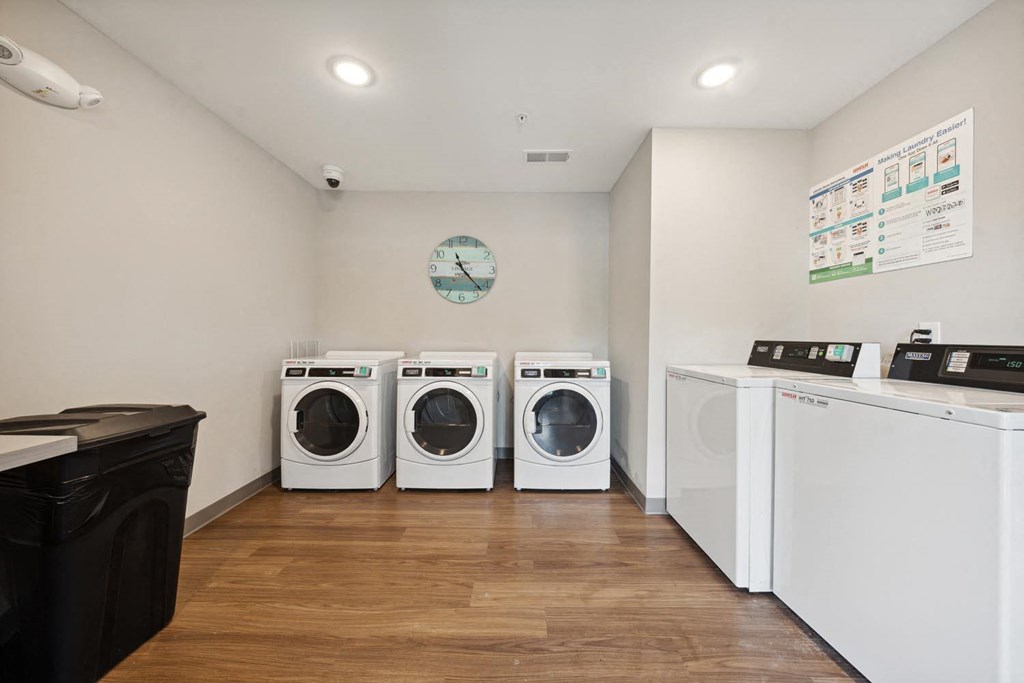 a laundry room with four washing machines and a clock on the wall