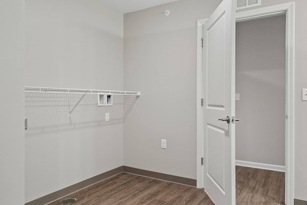 the closet in a bedroom of a home with white walls and wood floors