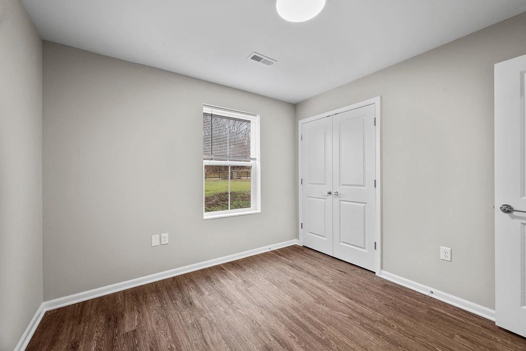 A room with a white door and a window with a view of a green lawn.