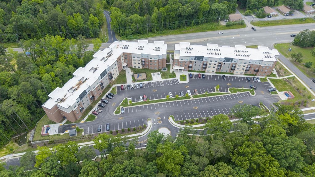 An aerial view of a large building complex surrounded by a parking lot and trees.