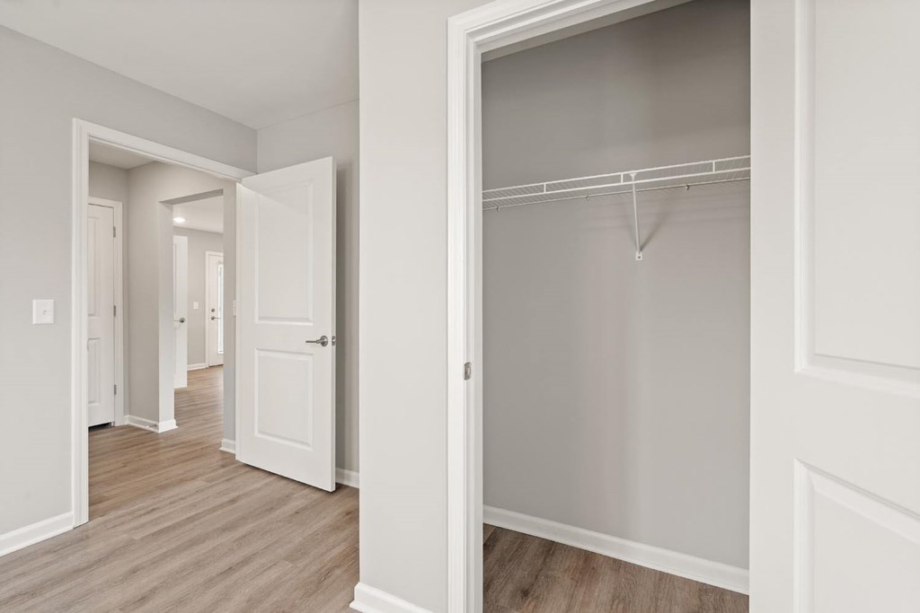 A white closet with a hanger rod is in the middle of a hallway.