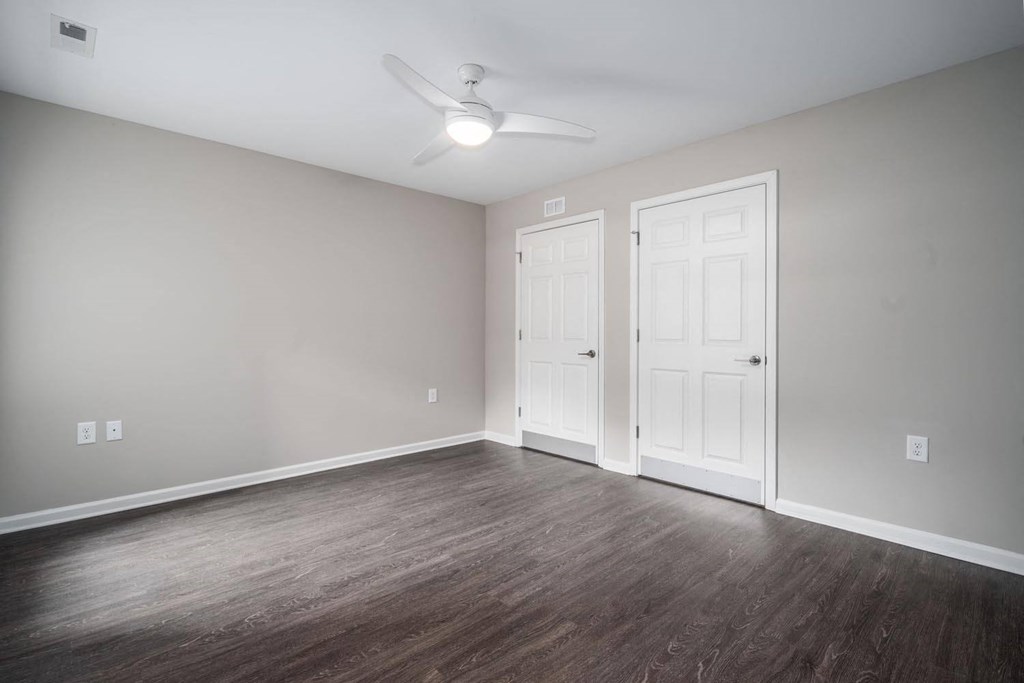 an empty living room with wood floors and a ceiling fan