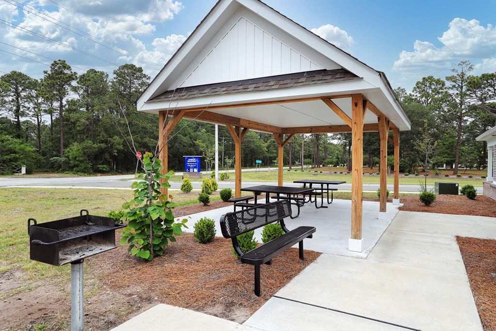 a picnic shelter with benches and a barbecue grill