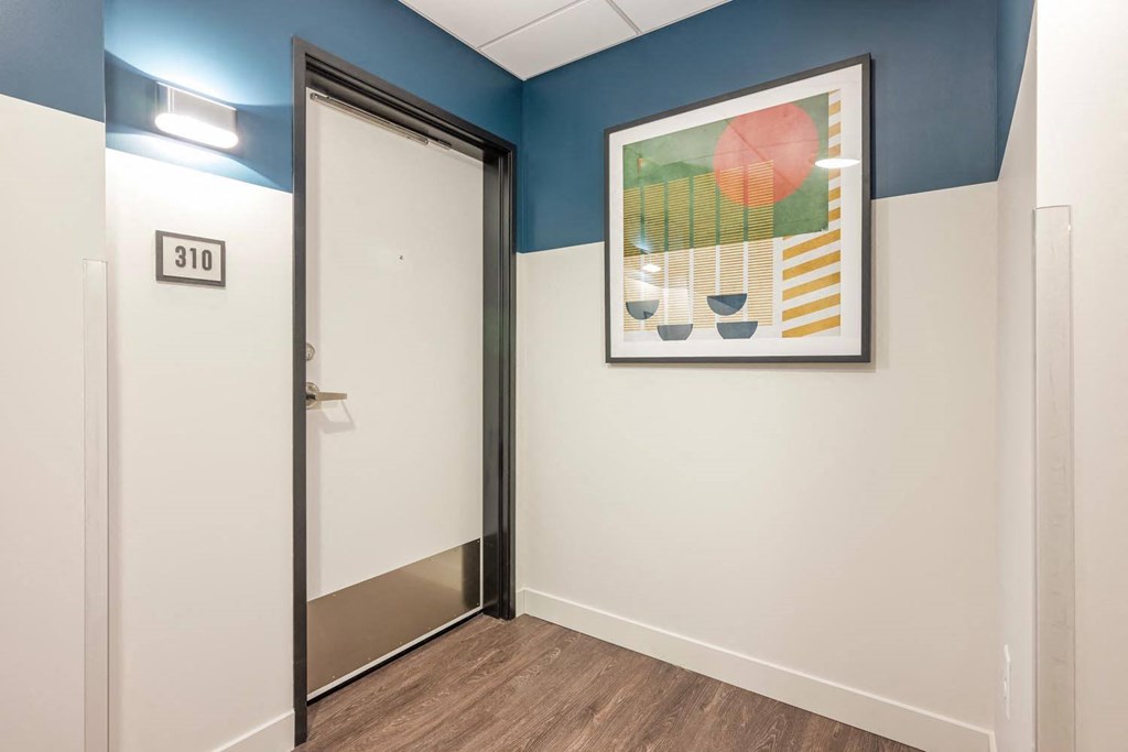 a hallway with a white door and a painting on the wall