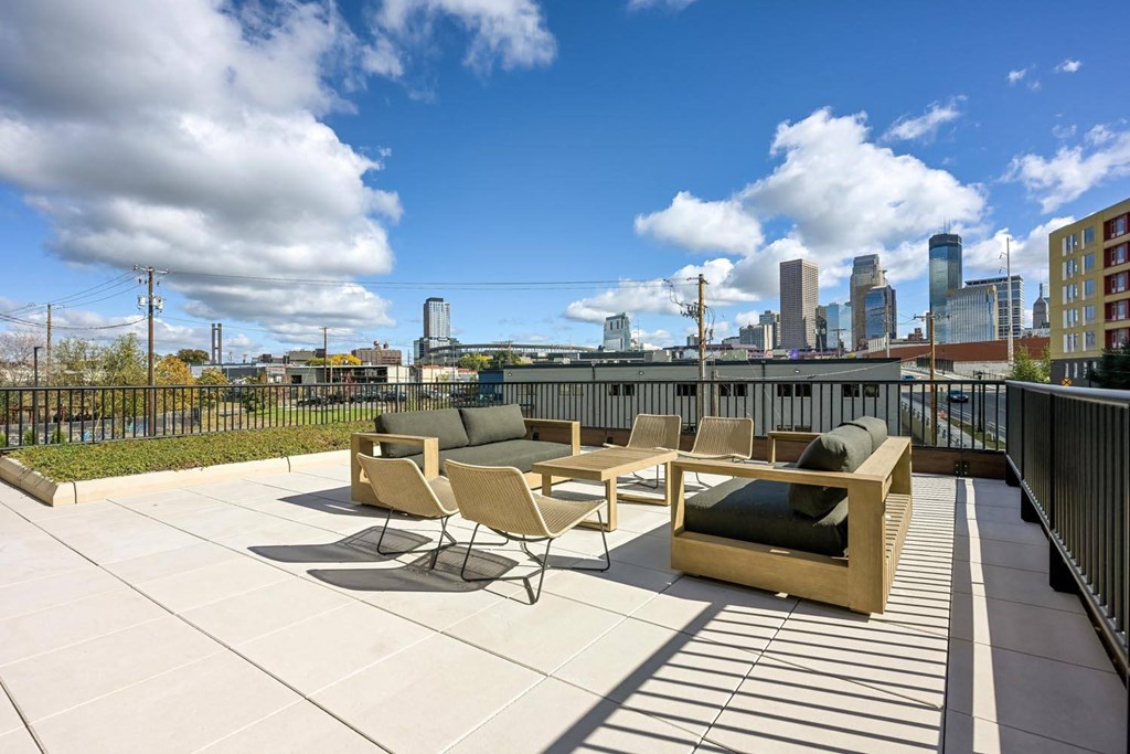 a roof deck with furniture and a city in the background