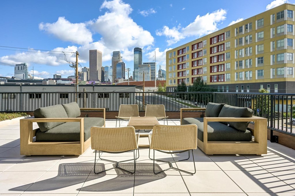 a rooftop patio with chairs and tables and a city in the background