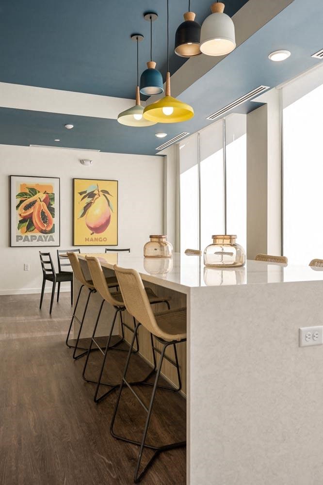a kitchen with a long white counter and chairs
