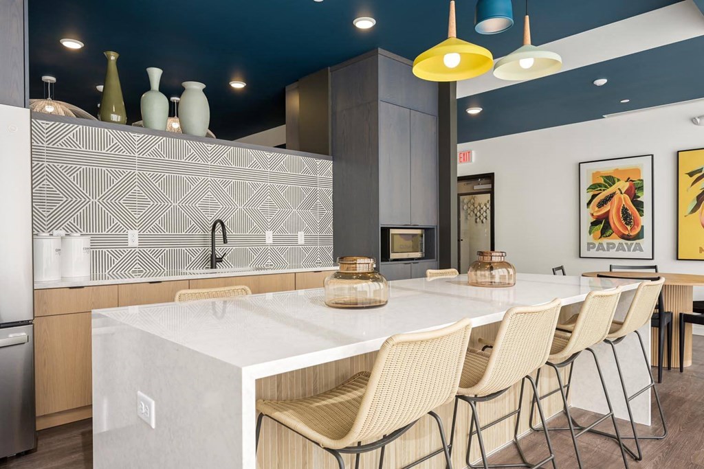 a kitchen with a large white counter and chairs